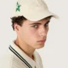 Cream baseball cap with tone-on-tone "Golden" patch and green star pin