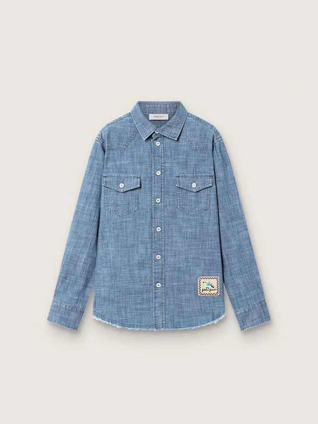 Journey unisex shirt in light blue cotton chambray with fringed hem and embroidered patch
