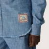 Journey unisex shirt in light blue cotton chambray with fringed hem and embroidered patch