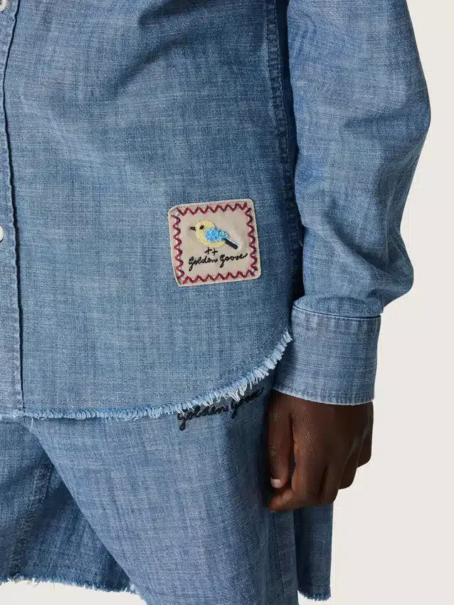 Journey unisex shirt in light blue cotton chambray with fringed hem and embroidered patch