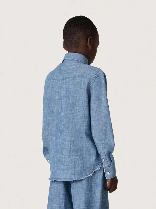 Journey unisex shirt in light blue cotton chambray with fringed hem and embroidered patch
