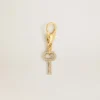 Key-shaped charm in gold-colored brass with crystals