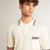 Men's worn-white knitted polo shirt with blue ribbing