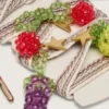 Skins cream and dove-gray striped embroidered laces with three fruit beaded charms