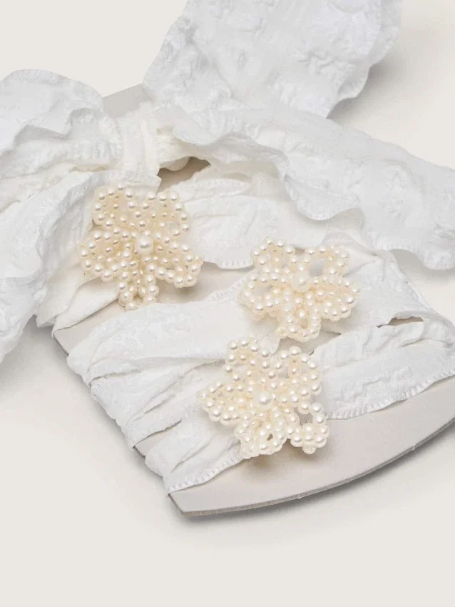 Skins white crinkle laces with flower-shaped beaded appliqués